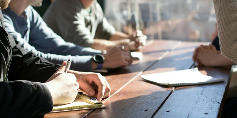Picture of people sitting at a table with a notebook on the table